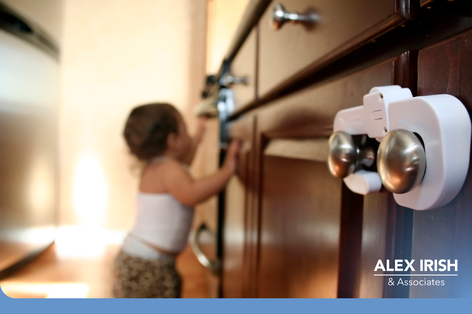 Childproof lock on the handle of two cabinets with a blurred child in the background