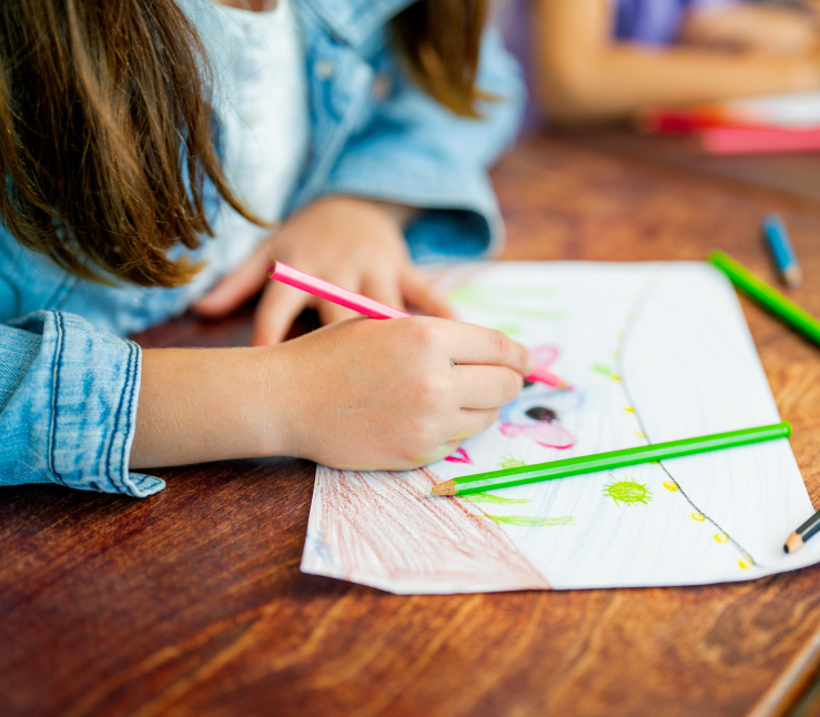 A girl colouring with pencil crayon